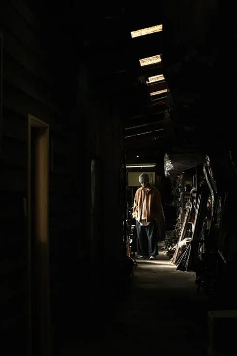 A man standing at the end of dark corridor filled with machinery parts